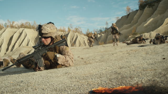 Kader-von-voll-ausgestatteten-und-bewaffneten-Soldaten,-die-während-der-militärischen-Operation-in-der-Wüste-kriechen.-Slow-Motion.
