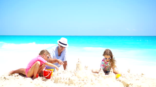 Vater-und-kleine-Kinder-machen-Sandburg-am-tropischen-Strand
