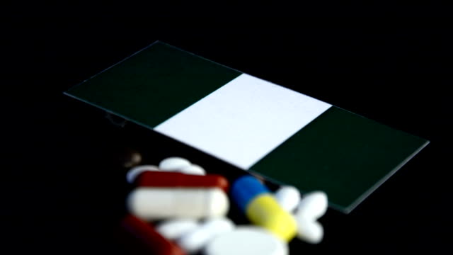 Bandera-Nigeria-con-gran-cantidad-de-píldoras-médicas-aisladas-sobre-fondo-negro