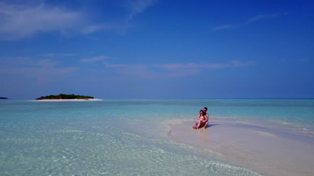 v03960-Aerial-flying-drone-view-of-Maldives-white-sandy-beach-2-people-young-couple-man-woman-romantic-love-on-sunny-tropical-paradise-island-with-aqua-blue-sky-sea-water-ocean-4k