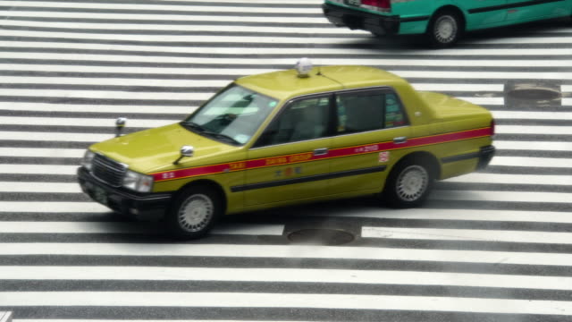 Taxis-und-Autos,-die-Überquerung-der-berühmten-beschäftigt-Shibuya-Bahnhof-Tokio-Kreuzung-in-Japan