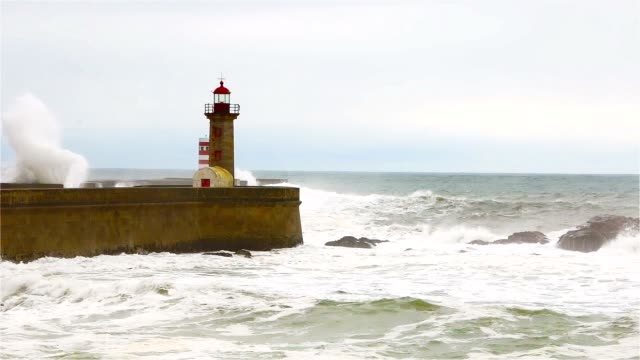 Starke-Wellen-brechen-über-die-Pier,-der-Leuchtturm-an-der-Küste-des-Atlantischen-Ozeans