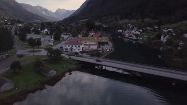 4K-Aerial-View-kleine-Stadt-mit-Wasser,-Brücken-und-Berge-in-Ferne