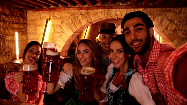 Young-multi-ethnic-friends-celebrating-Oktoberfest-with-beer-and-taking-selfies