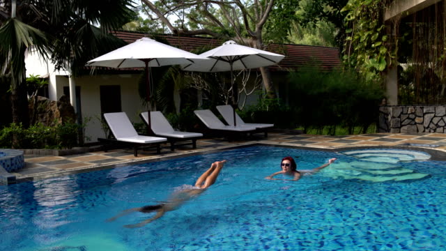 Las-mujeres-nadan-en-la-piscina-al-aire-libre.-Chica-se-zambulle-y-nada-bajo-el-agua