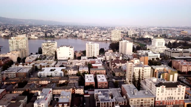 Al-atardecer-cae-sobre-los-edificios-y-la-ciudad-de-Oakland,-California-y-lago-Merritt
