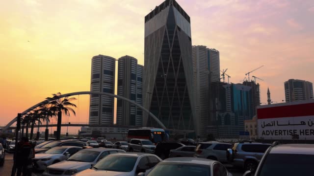 Sharjah-city-towers,-bridge,-street-at-sunset