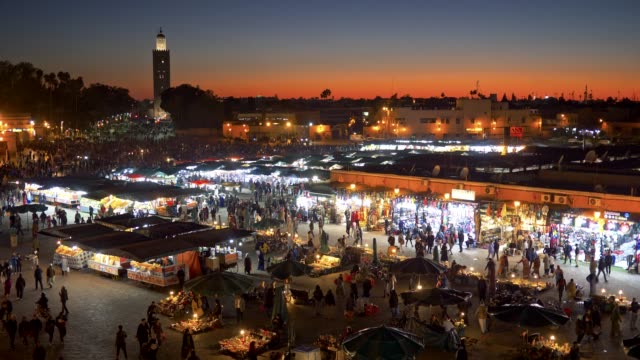Crowds-of-people-passing-through-the-market-place-at-the-Jemaa-el-Fnaa-Square-in-Marrakesh,-Morocco-right-after-sunset.-4K,-UHD