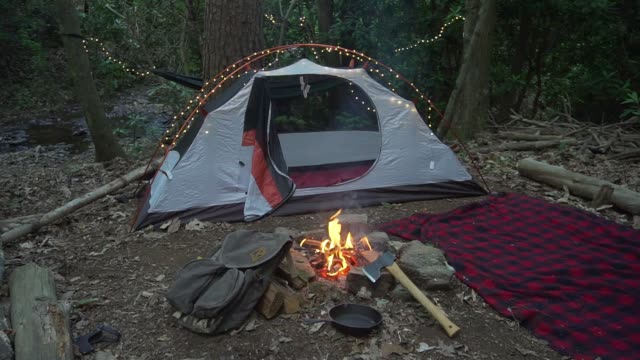 Bushcraft-Campingplatz-in-der-Wildnis-mit-Lagerfeuer,-Axt-und-Decke.