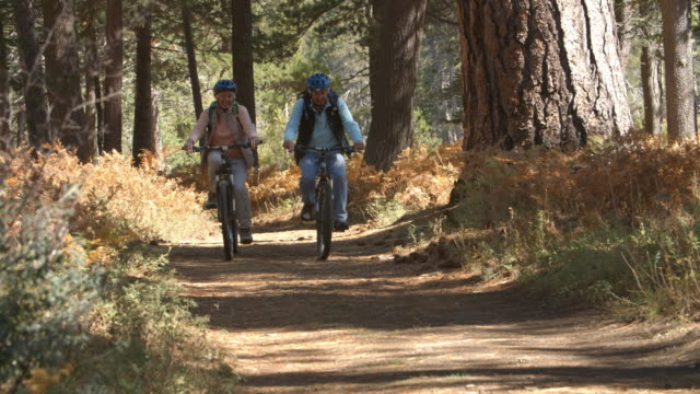 Pareja-Senior-Ciclismo-en-el-bosque,-el-sendero-de-movimiento-lento