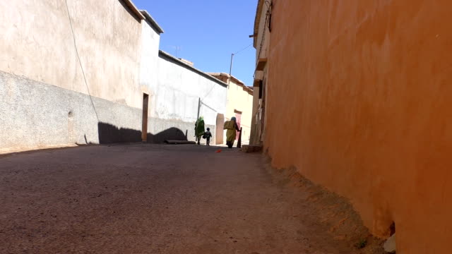 Two-women-and-kid-walking-in-African-village-street