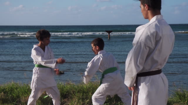 Glücklich-Karate-Sport-Lehrer-beobachten-Jungen-kämpfen-und-Training