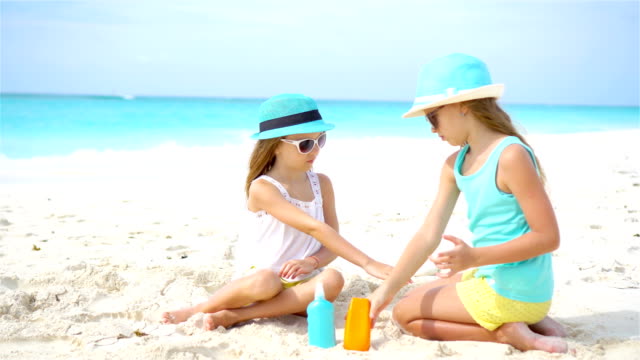 Kids-applying-sun-cream-to-each-other-on-the-beach.-The-concept-of-protection-from-ultraviolet-radiation