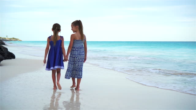 Little-girls-walking-by-the-sea-on-the-white-beach.-Kids-on-beach-vacation-in-the-evening