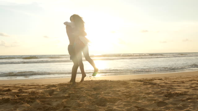 Happy-couple-kissing-and-hugging-each-other-at-the-sea-beach-at-sunset.-Young-man-and-woman-in-love-having-fun-together-at-beautiful-ocean-shore-during-summer-holidays-or-vacations.