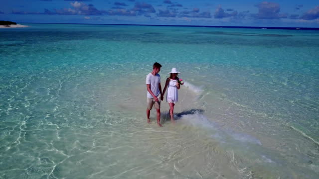 v03932-Aerial-flying-drone-view-of-Maldives-white-sandy-beach-2-people-young-couple-man-woman-romantic-love-on-sunny-tropical-paradise-island-with-aqua-blue-sky-sea-water-ocean-4k
