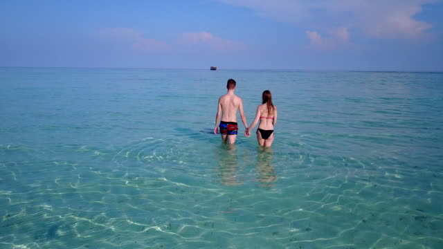 v04004-fliegenden-Drohne-Luftaufnahme-der-Malediven-weißen-Sandstrand-2-Personen-junges-Paar-Mann-Frau-romantische-Liebe-auf-sonnigen-tropischen-Inselparadies-mit-Aqua-blau-Himmel-Meer-Wasser-Ozean-4k