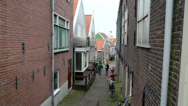 Dos-personas-caminando-por-la-estrecha-calle-en-Volendam