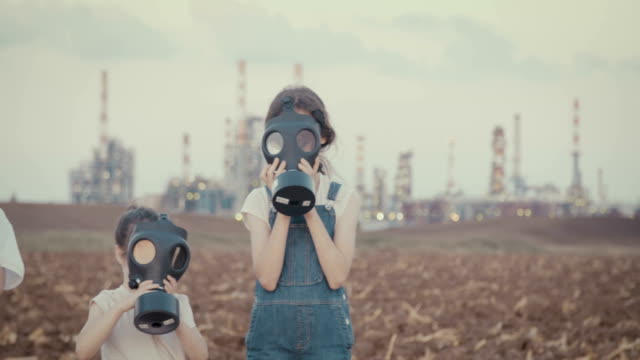 Save-the-plant.-Kids-wearing-gas-masks-near-a-large-oil-refinery