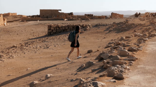 Mädchen-mit-Rucksack-erkundet-Wüste-Ruinen.-Ziemlich-europäische-Reisende-wandelt-unter-alten-Landschaft.-Masada-Israel-4K