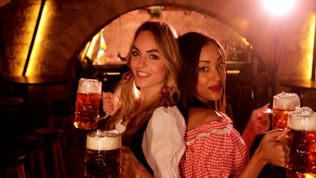 Young-multi-ethnic-women-in-Bavarian-costumes-celebrating-Oktoberfest-with-beer