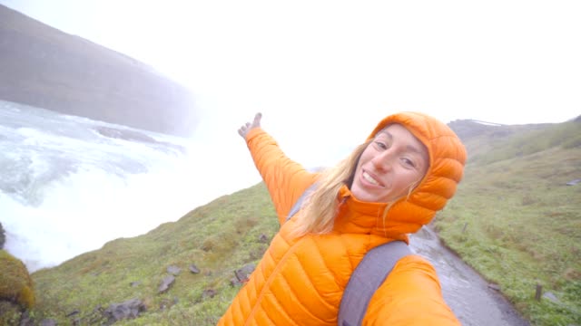 4K-Selfie-portrait-of-young-woman-near-huge-waterfall,-Iceland