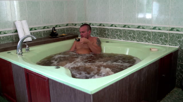 Ein-Mann-sitzt-in-das-Kräuterbad-mit-Mineralwasser-Getränke-Tee-und-knetet-seinen-Hals