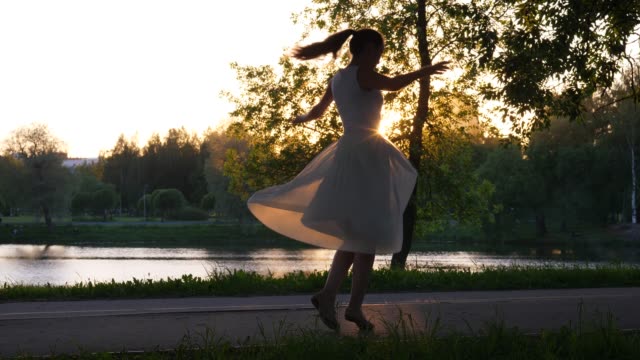 Glückliche-Frau-tanzt-im-Park-bei-Sonnenuntergang