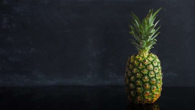 Stop-motion-ripe-tropical-fruit-pineapple-on-a-black-background.-Time-lapse-food-loop-footage
