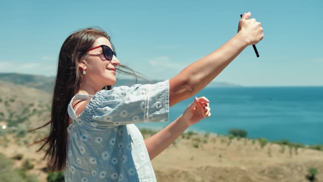 Portrait-of-elegant-European-traveler-woman-taking-selfie-using-smartphone