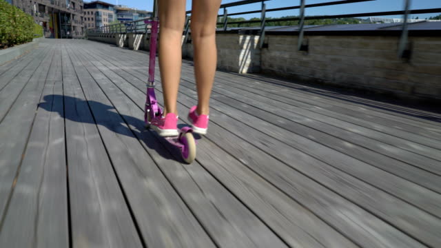 Teenage-girl-riding-a-Kick-Scooter-on-the-wooden-promenade.