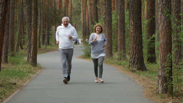 Glücklich-älterer-Mann-und-Frau-im-Park-joggen