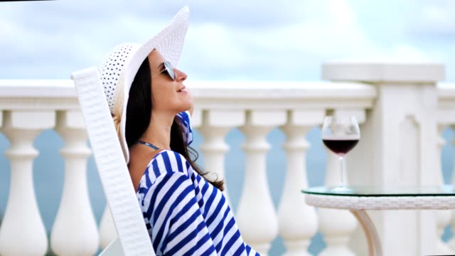 Attractive-female-tourist-enjoying-wonderful-seascape-at-embankment-with-goblet-of-red-wine