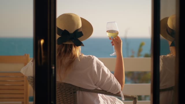 Mujer-que-tiene-buen-tiempo-bebiendo-vino-en-el-balcón-con-vistas-al-mar