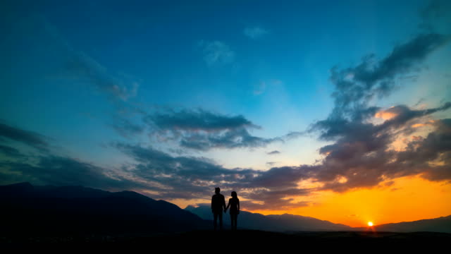 Das-Paar-steht-auf-einem-Berg-gegen-einen-Sonnenuntergang-mit-Nordlicht