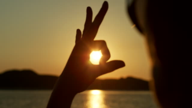 Silhouette-Of-Woman-Making-Shapes-With-Hands-Against-Sun