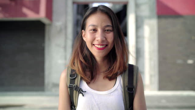 Cheerful-beautiful-young-Asian-backpacker-woman-feeling-happy-smiling-to-camera-while-traveling-at-Chinatown-in-Beijing,-China.-Lifestyle-backpack-tourist-travel-holiday-concept.