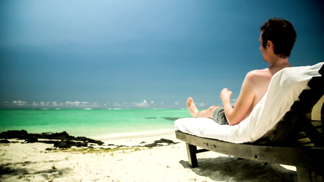 Man-relaxing-in-sun-chair-at-beach
