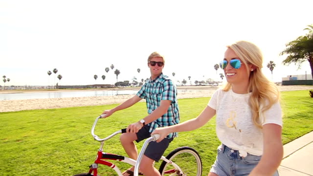 Montar-bicicletas-de-pareja-joven-feliz-en-la-playa-de-estilo-de-vida-de-verano-de-alta-definición