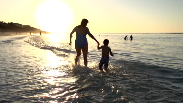 Mutter-und-Kind-spielen-am-Strand-auf-silhouette-bei-Sonnenuntergang,-Cape-Town