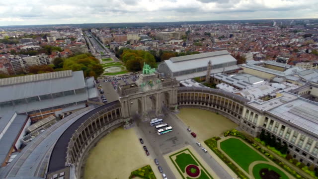 Aerial-view-Brussels,-Parc-du-Cinquantenaire-U-shaped-arcade.-Beautiful-aerial-shot-above-Europe,-culture-and-landscapes,-camera-pan-dolly-in-the-air.-Drone-flying-above-European-land.-Traveling-sightseeing,-tourist-views-of-Belgium.