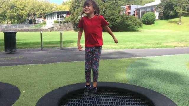 Chica-feliz-saltos-y-rebotar-en-el-trampolín-al-aire-libre