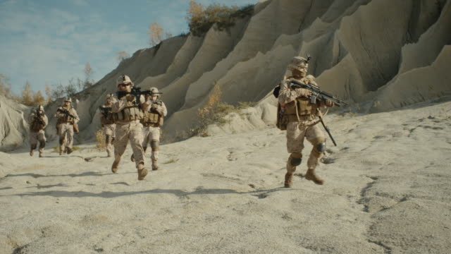 Squad-of-Fully-Equipped,-Armed-Soldiers-Running-in-the-Desert.-Show-Motion.