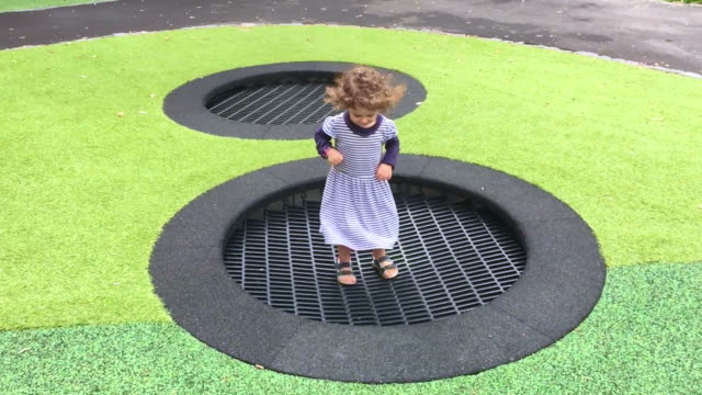Happy-little-girl-jumps-and-bounce-in-slow-motion-on-outdoor-trampoline