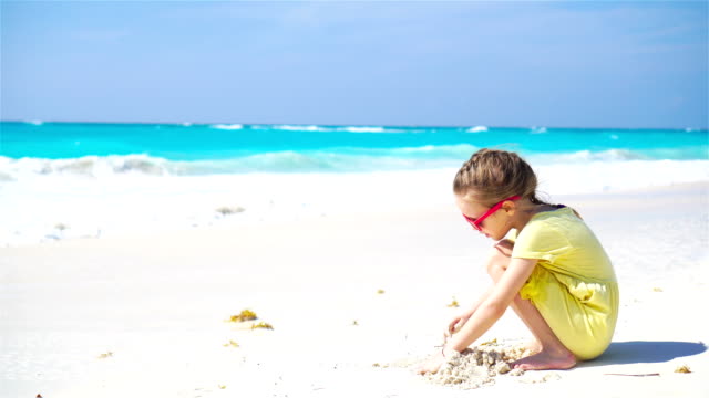 Entzückende-kleine-Mädchen-spielen-am-Strand-mit-sand