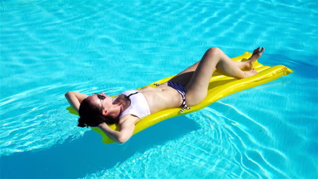 Frau-entspannend-auf-aufblasbare-Luftmatratze-im-türkisfarbenen-Wasser