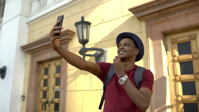 Hombre-afroamericano-turístico-tener-chat-de-vídeo-en-línea-usando-su-smartphone-cámara-mientras-viaja-en-Europa