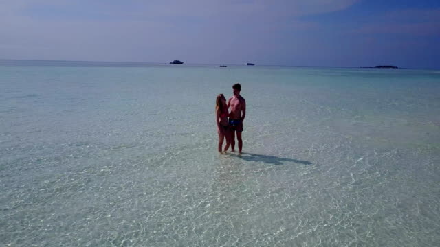 v03981-fliegenden-Drohne-Luftaufnahme-der-Malediven-weißen-Sandstrand-2-Personen-junges-Paar-Mann-Frau-romantische-Liebe-auf-sonnigen-tropischen-Inselparadies-mit-Aqua-blau-Himmel-Meer-Wasser-Ozean-4k