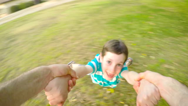 POV-footage-of-father-swinging-his-son-outdoors