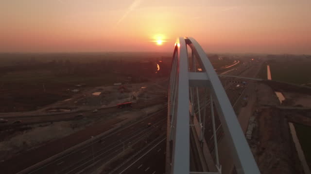 Nuevo-puente-construido-sobre-una-carretera-con-tráfico,-en-puesta-de-sol